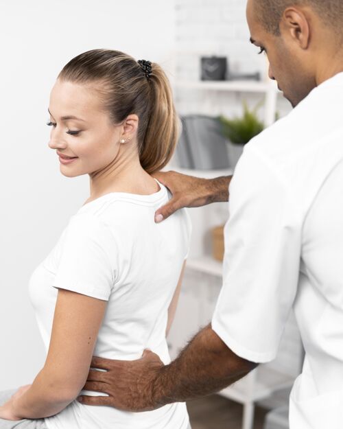 男人男理疗师检查女人的背痛理疗男人疼痛