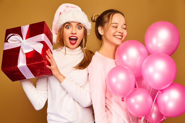 新年圣诞节带着大礼盒和粉色气球的模特们圣诞老人友好姐妹