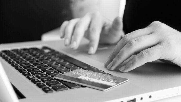 信贷黑白视图的信用卡躺在笔记本电脑键盘上网上购物和电子商务的概念密码屏幕电子商务